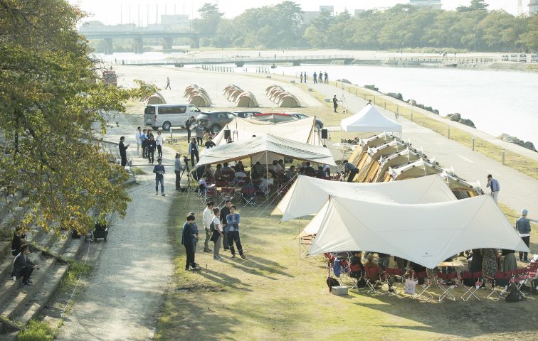 河川敷にテントが設営され、賑わっている様子